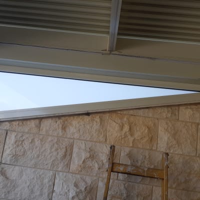 מסגרת אלומיניום לחלון משולש על קיר אבן