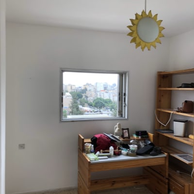 חדר עם קירות לבנים ומנורת שמש צהובה