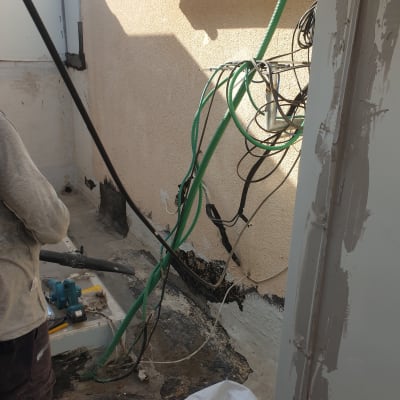 אדם עובד על איטום קיר עם כלים וחומרים