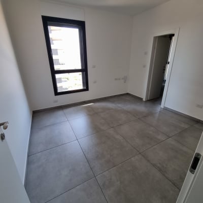 חדר ריק עם רצפת אריחים נקייה וחלון גדול