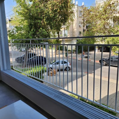 מעקה מתכת לבן במרפסת עם נוף לרחוב