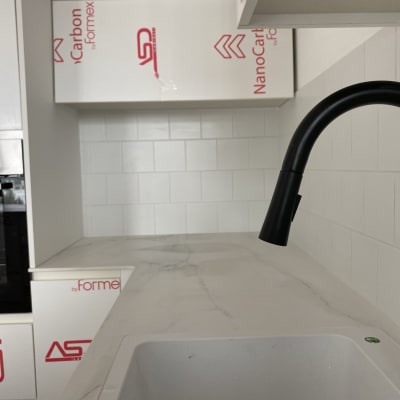 מטבח בשיפוץ עם ארונות מכוסים בניילון וברז חדש