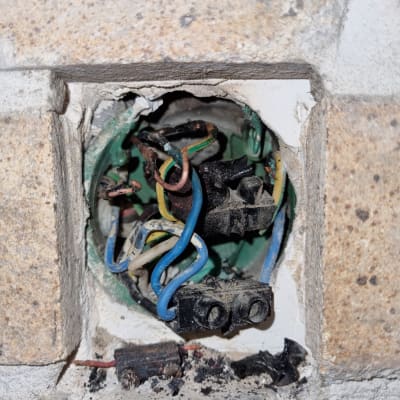 חוטי חשמל צבעוניים בקופסת חיבורים בקיר