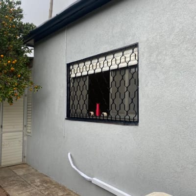 קיר צבוע באפור עם חלון וסורג שחור