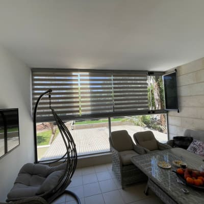 מרפסת עם כיסאות ושולחן, וילונות גלילה מותקנים