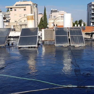 גג אטום בזפת עם דודי שמש וקולטים
