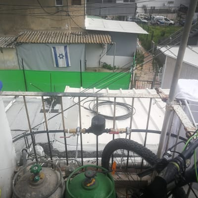 צינור מים כחול מחובר למיכל גז על מרפסת