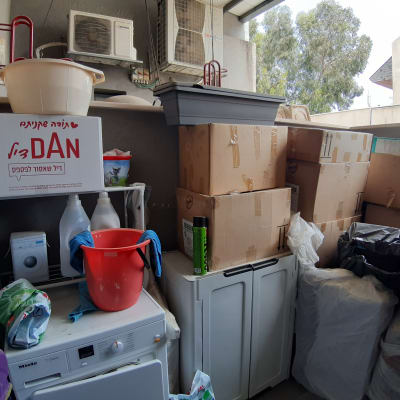 קופסאות קרטון, דלי אדום, חומרי ניקוי, מכונת כביסה