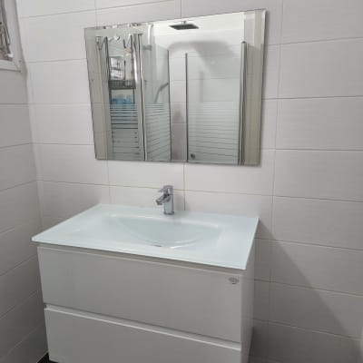 כיור לבן עם ברז מתכת ומראה על הקיר