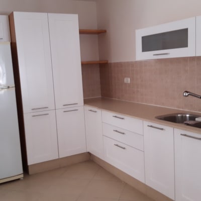 מטבח עם ארונות לבנים, כיור וברז, מקרר לבן