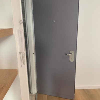 דלת מתכת אפורה עם ידית כסופה פתוחה חלקית