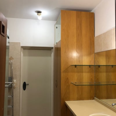 חדר אמבטיה עם ארון עץ ומדפים מזכוכית