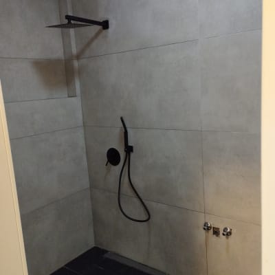 מקלחת עם אריחים אפורים וברזים מותקנים