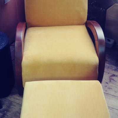 כורסה מרופדת בצבע צהוב עם הדום תואם