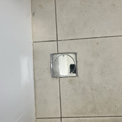 פתח ניקוז מרובע עם מכסה עגול על רצפה