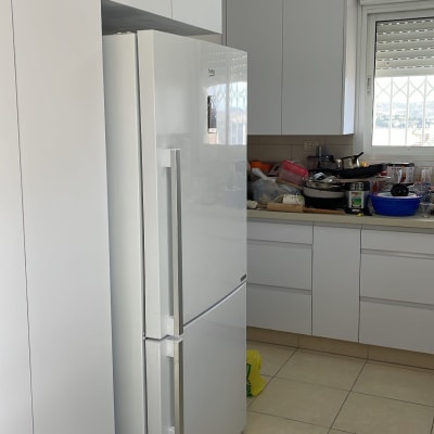 מטבח עם מקרר לבן וארונות לבנים