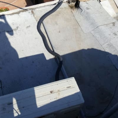 גג עם צינור שחור ומזגן, צל של אדם