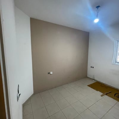 חדר ריק עם קיר צבוע, מנורה תלויה ותשתית חשמל.