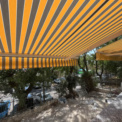 סוככים עם פסים צהובים ואפורים תלויים מעל מרפסת