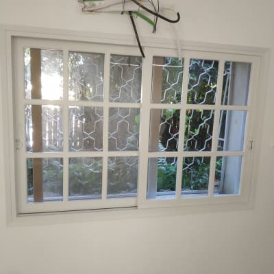 חלון עם מסגרת לבנה וקיר צבוע בלבן