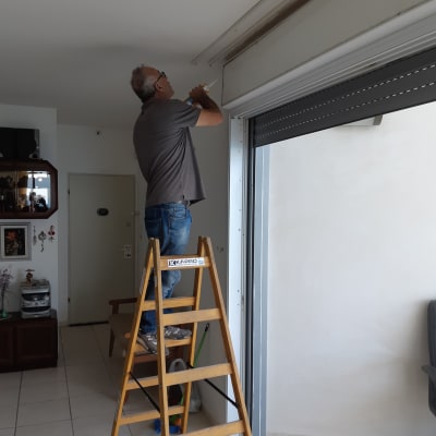 אדם עובד על מסגרת אלומיניום של חלון