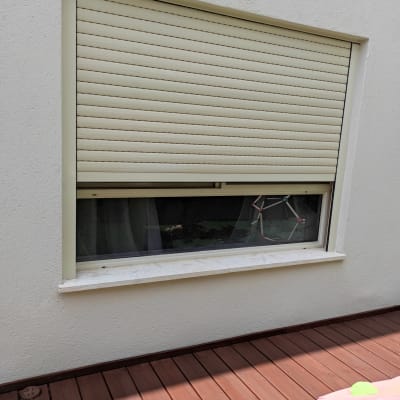 תריס גלילה סגור על חלון עם מסגרת לבנה