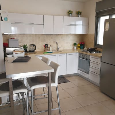 מטבח מודרני עם ארונות לבנים ושולחן גבוה