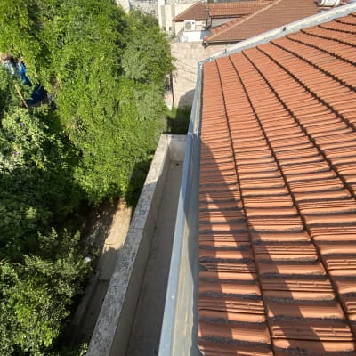 גג רעפים אדומים עם מרזב מתכת בצד