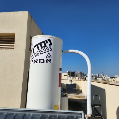 דוד שמש עם צינור לבן על גג בניין