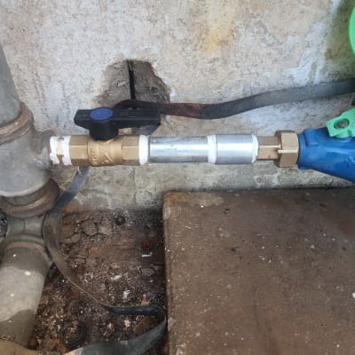 צינור מתכת עם ברז פלסטיק שחור על קיר בטון