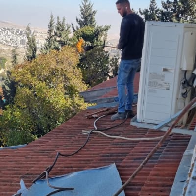 אדם על גג עם מבער להלחמת יריעות איטום