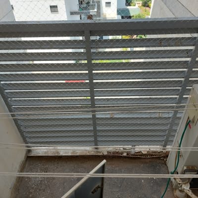רשת מתכת על מרפסת עם חוטי כביסה ומזגן