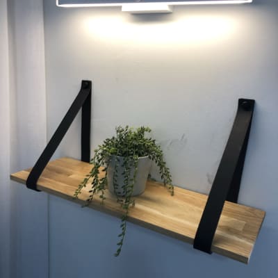 מדף עץ עם תומכים שחורים וצמח בעציץ
