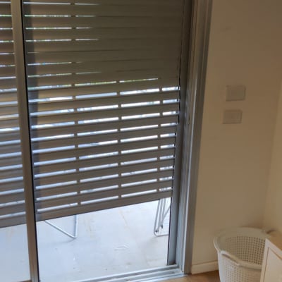 תריסים אפורים חצי פתוחים על דלת זכוכית