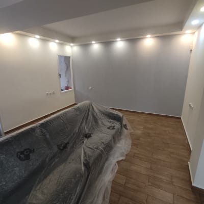 חדר צבוע עם קיר אפור, רהיטים מכוסים בניילון