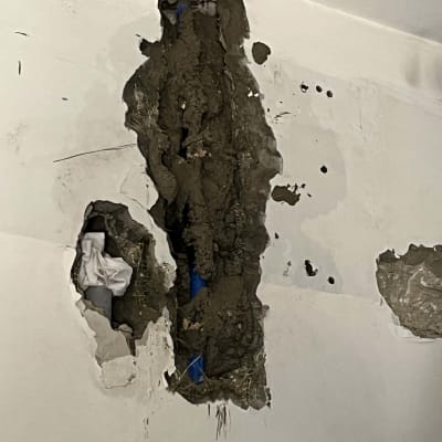 קיר עם חור גדול וצינור כחול חשוף