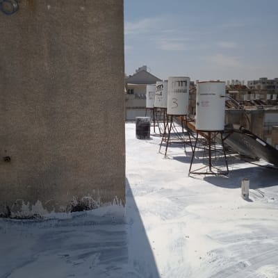 גג עם חומר איטום לבן ומיכלים על רגליים