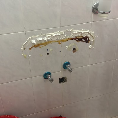 קיר עם חורים, ברזים ודלי אדום