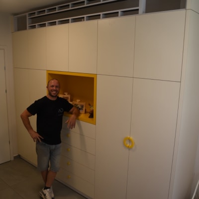 נגר עומד ליד ארון עם ידיות צהובות