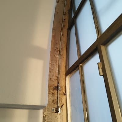 מסגרת חלון מתכתית עם זכוכית חלבית וקיר צבוע