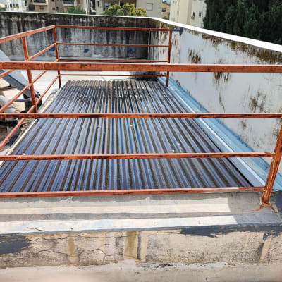 גג עם מעקה מתכת חלוד ורצפת פח גלי