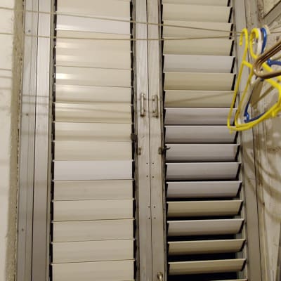 תריסים לבנים עם מסגרת מתכת בחלון