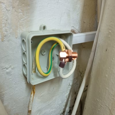 תיבת חיבורים עם חוטי חשמל חשופים על קיר