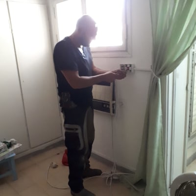 אדם עובד על חיבור חשמלי של מזגן על קיר