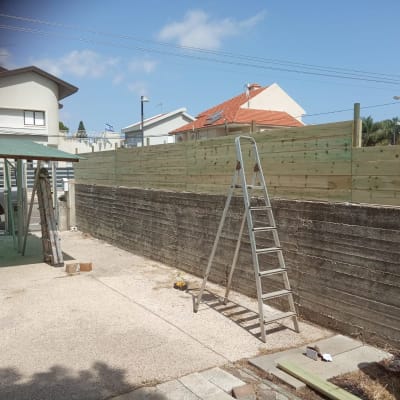 סולם מתכת ליד גדר עץ חדשה בחצר