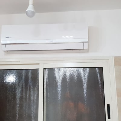 מזגן לבן מותקן על קיר מעל חלון