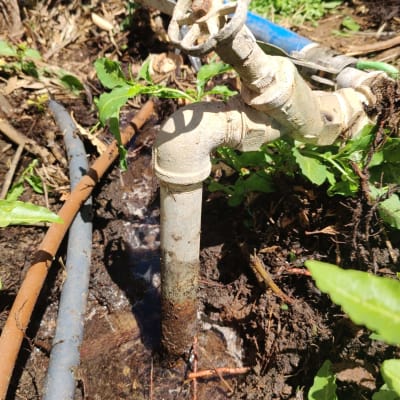 ברז מים חלוד עם צינורות בגינה