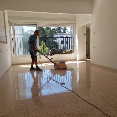 אדם מנקה רצפה עם מכונת פוליש בחדר ריק