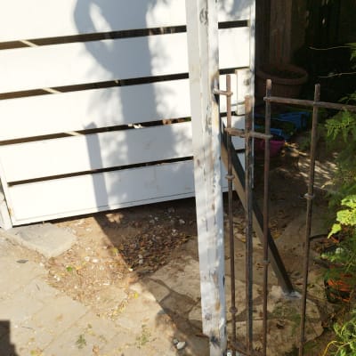 שער מתכת לבן עם מסגרת ברזל חלודה