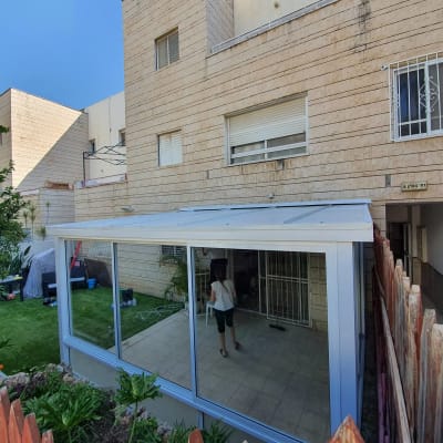 מבנה אלומיניום עם חלונות זכוכית בחצר